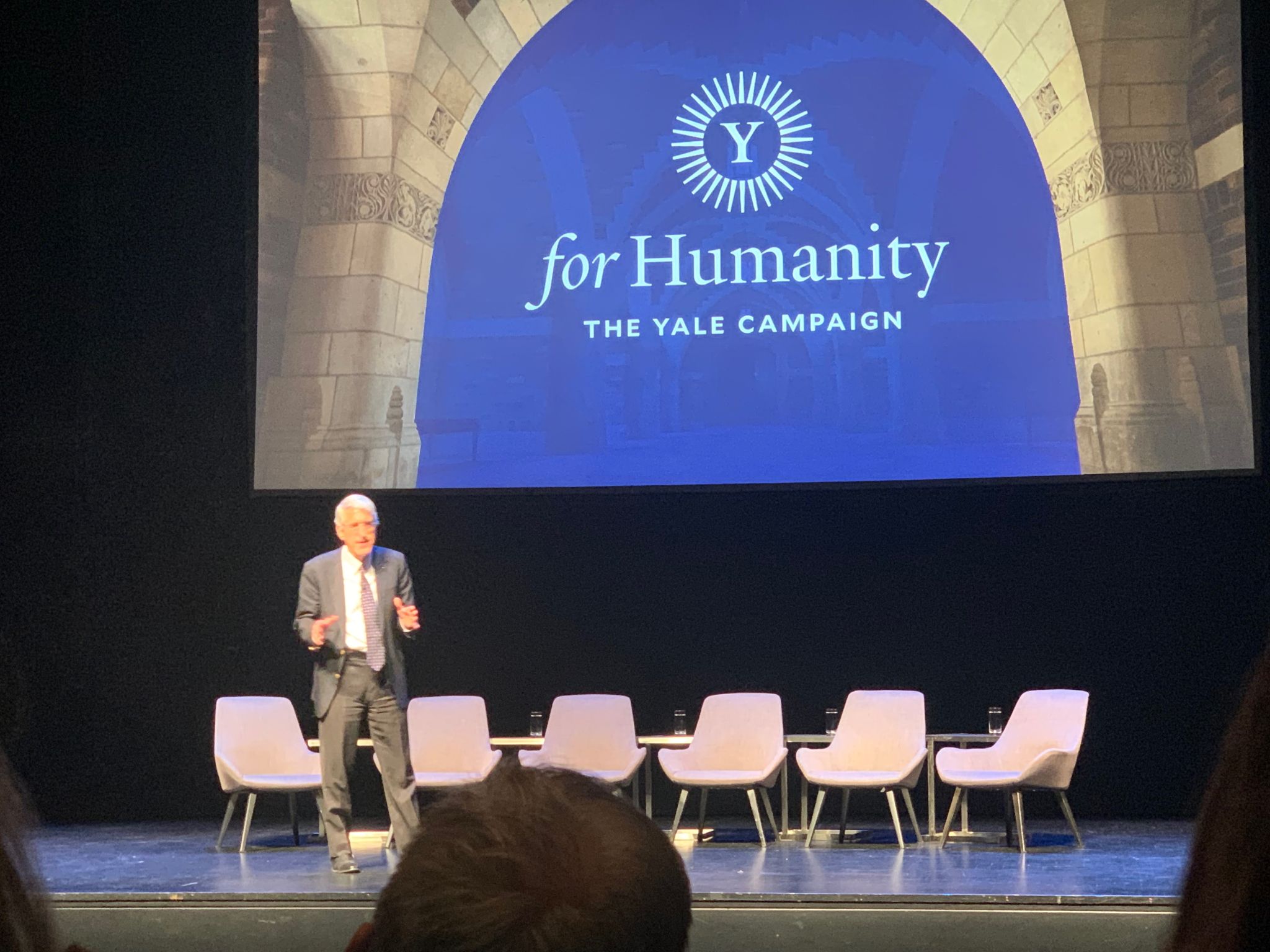 Peter Salovey speaking on stage in front of a Yale for Humanity banner