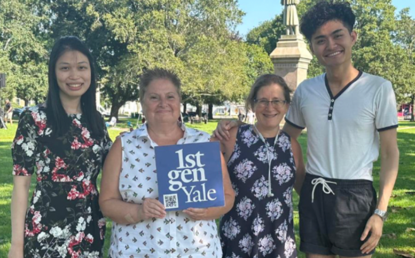 Four people stand outside and hold a 1stGenYale sign