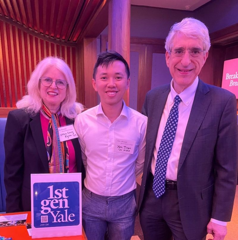 Three alums stand at a table behind a 1stGenYale sign